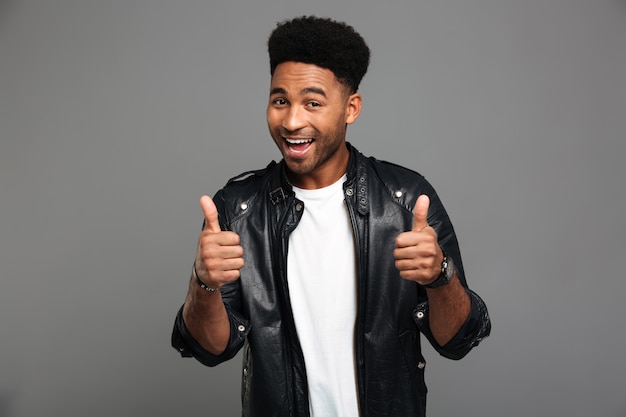 Close-up portrait of african slylish man showing thumbs up gesture with two hands, looking