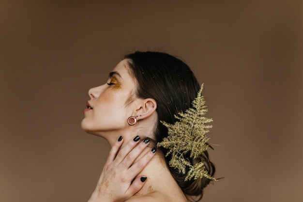 Close-up portrait of amazing brunette girl. Attractive caucasian woman posing with plant in hair.