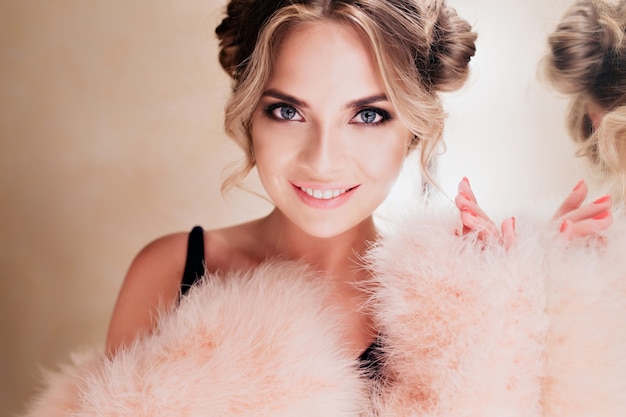 Free photo close-up portrait of amazing happy female artist with hollywood smile standing in dressing room after performance. pretty young woman in pink fluffy attire posing next to make-up mirror