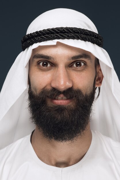 Close up portrait of arabian saudi sheikh. Young male model standing and smiling, looks happy.