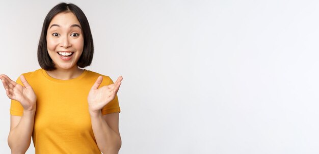 Close up portrait of asian woman looking surprised wow face staring impressed at camera standing ove