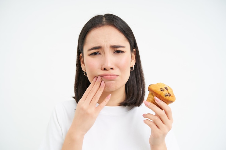 無料Photo toothcahe を持つアジアの女性の肖像画を間近します。カップケーキを見て甘すぎるデザートは白いバを食べることができません