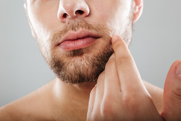 Close up portrait of bearded half men's face with hand