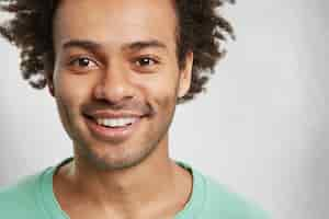 Free photo close up portrait of bearded handsome man with bristle and curly bushy hair, smiles broadly