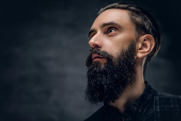 Close up portrait of bearded male looking up on a dark background.