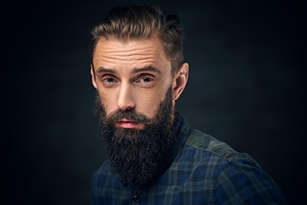 Close up portrait of bearded male with long hair over dark background.