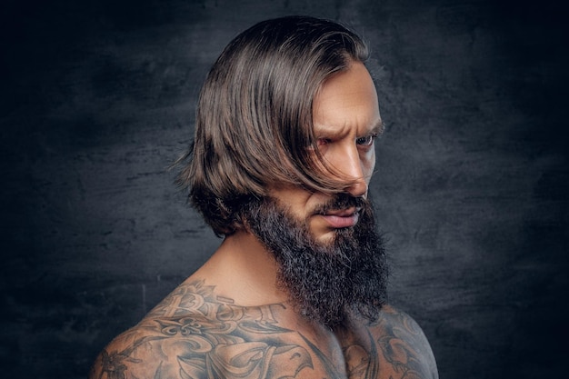 Close up portrait of bearded male with long hair and tattooed chest.