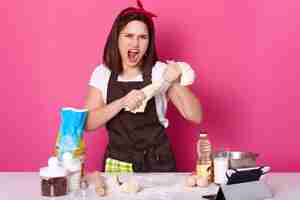 Free photo close up portrait of beautiful angry baker kneads dough and screams loud