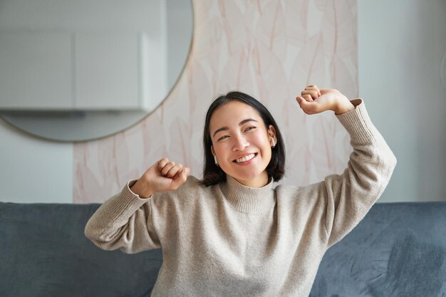 Close up portrait of beautiful asian girl dancing feeling happy and upbeat listening music in wirele