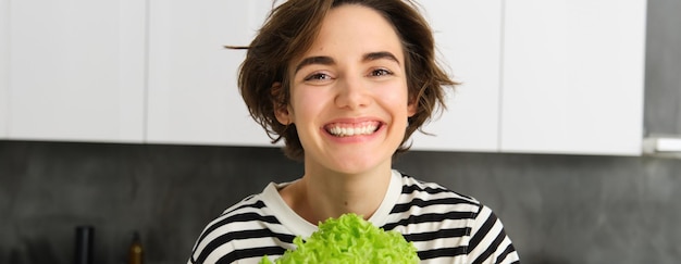 Foto gratuita ritratto ravvicinato di una bella donna sana e sorridente che posa con una dieta di cucina a foglia di lattuga verde