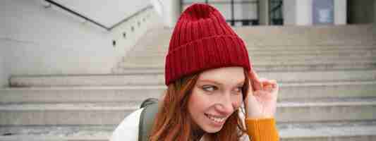 Free photo close up portrait of beautiful redhead girl in red hat urban woman with freckles and ginger hair