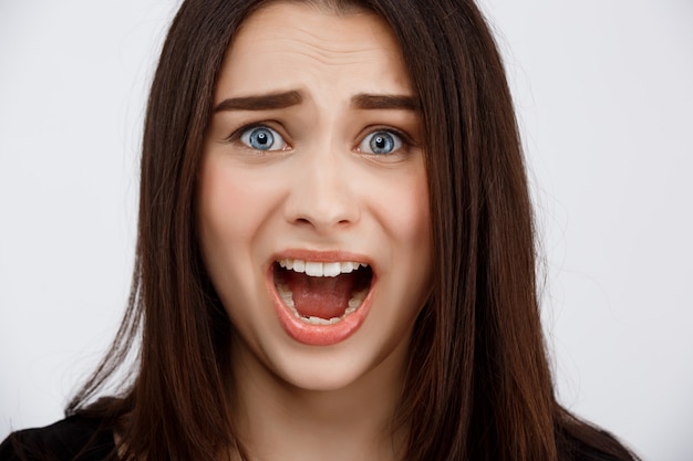 Close up portrait of beautiful scared brunette girl shouting