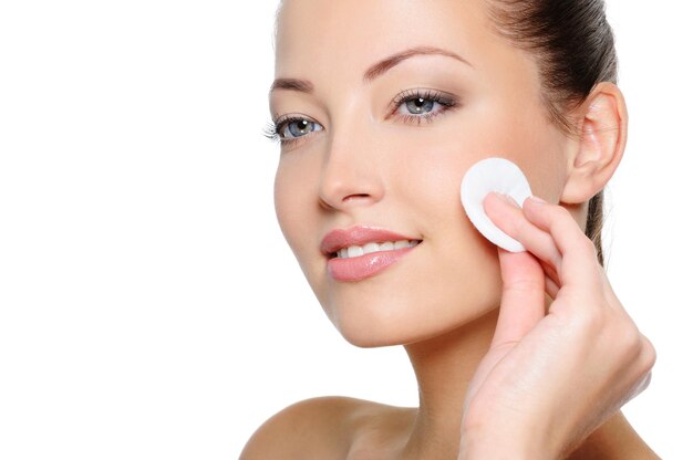 Close-up portrait of beautiful woman cleaning her pretty face with cotton swab