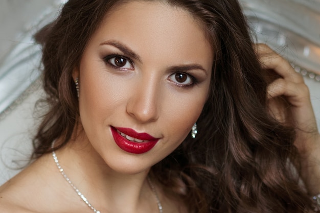 Close-up portrait of a beautiful woman with makeup and red lips, beautiful hair