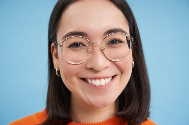 Close up portrait of beautiful young asian woman in glasses smiling and looking happy trying new eye