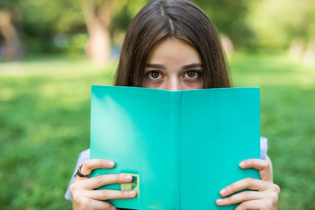 Foto gratuita ritratto del primo piano di una bella giovane donna con il libro nel parco