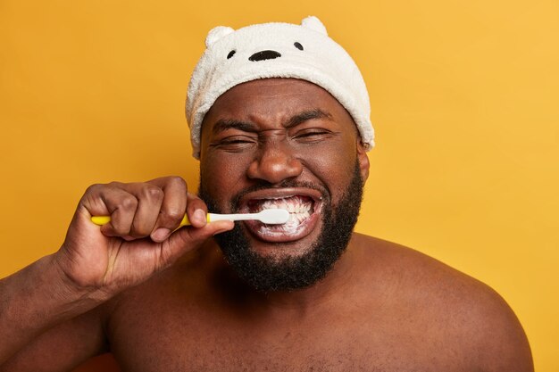 close up portrait of black afro man brushes teeth, has daily morning routine