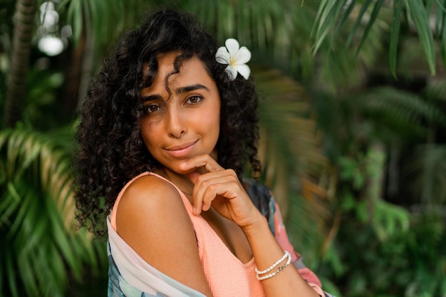 Close up portrait of  blissful woman with  plumeria flower in hairs after spa in   luxury resort Wearing boho tropical outfit