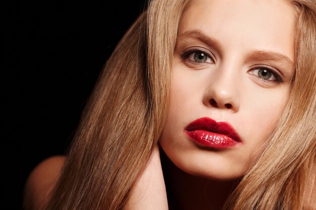Крупным планом портрет блондинки с макияжем и красными губами.