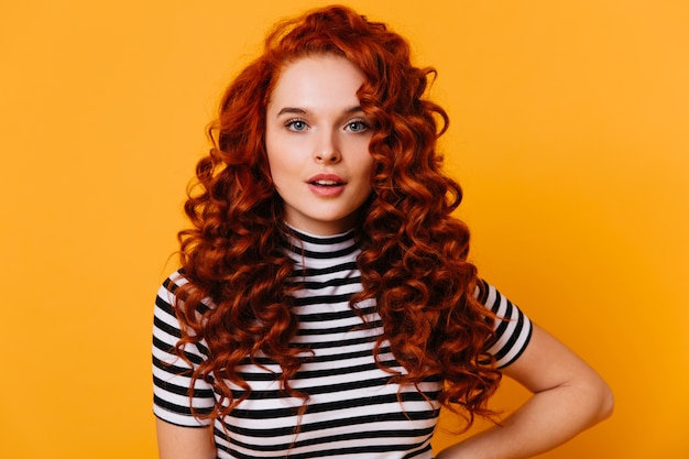 긴 속눈썹과 오렌지 공간에 대한 볼륨있는 붉은 곱슬 머리와 파란 눈 소녀의 클로즈업 초상화.