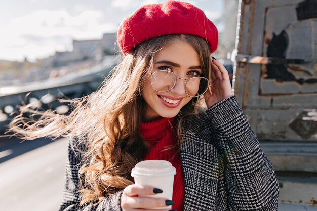 Close-up portrait of blue-eyed white woman with sincere smile posing on urban background in morning