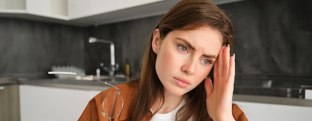 Free photo close up portrait of brunette woman touching head feeling unwell has headache or migraine sitting in