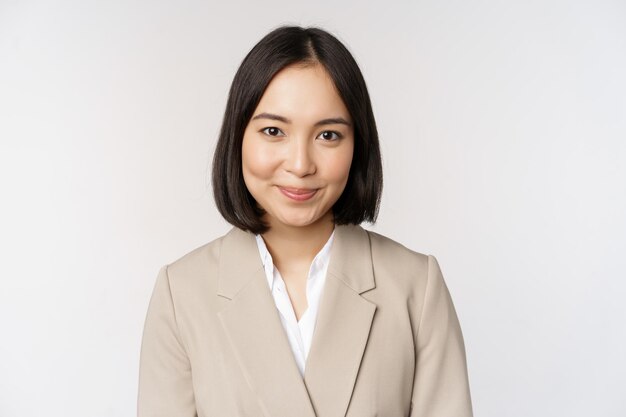 Close up portrait of businesswoman asian female entrepreneur in suit smiling and looking professional standing against white background