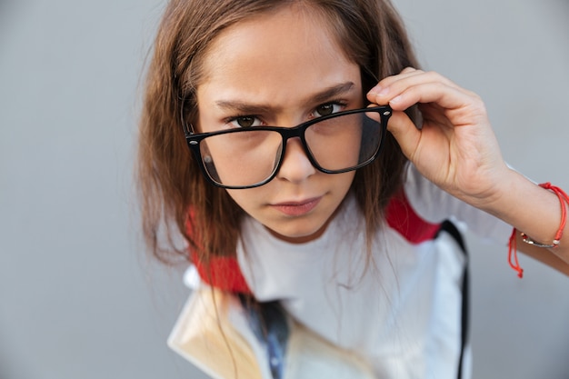Крупным планом портрет спокойной брюнетки школьница в очках
