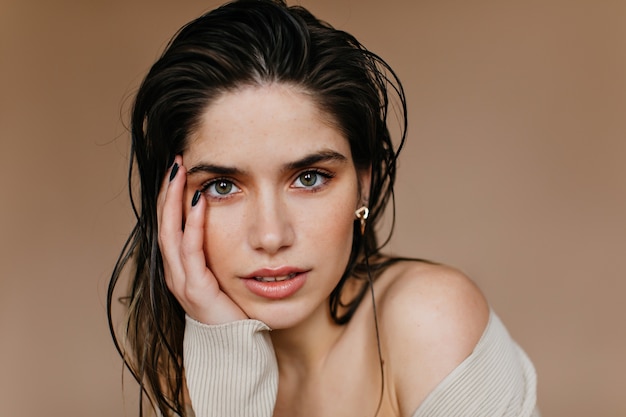 Close-up portrait of carefree brunette woman. Serious european lady posing on brown wall.