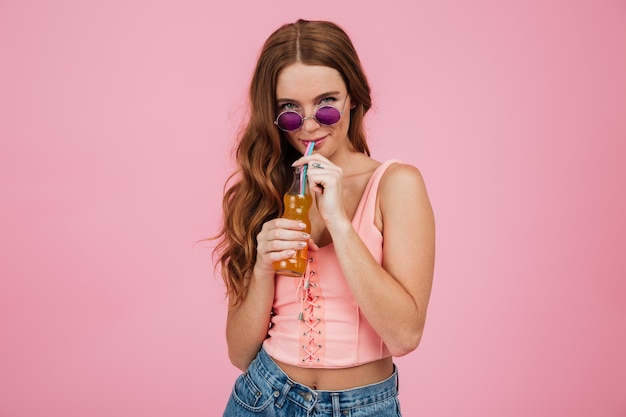 Close-up portrait of charming readhead woman in glasses, drinking orange soda