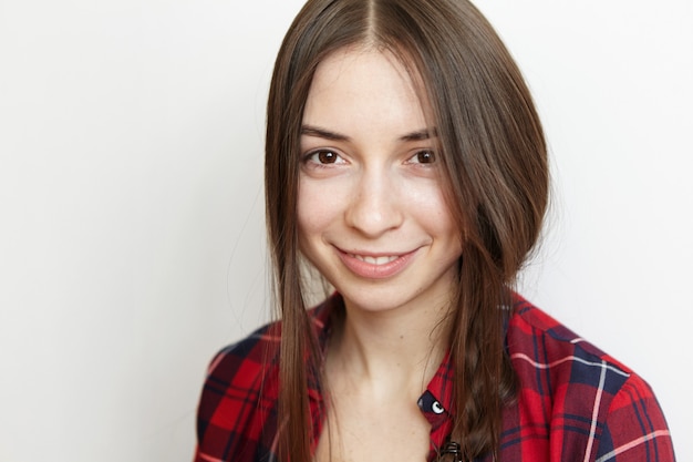 Foto gratuita chiuda sul ritratto di giovane donna castana allegra con il sorriso sveglio e la pelle pulita sana che indossa la sua treccia sudicia sul lato, sorridendo felicemente