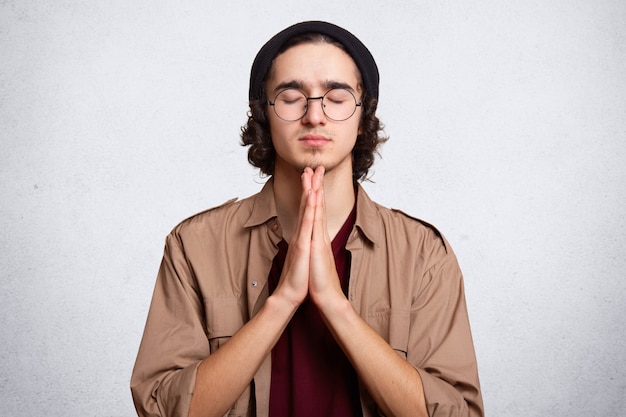 Free photo close up portrait of concentrated man keeps palms pressed together