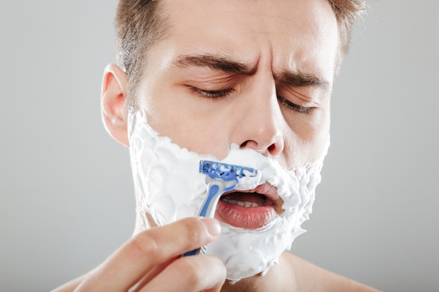 Foto gratuita ritratto di un uomo concentrato con schiuma da barba da vicino