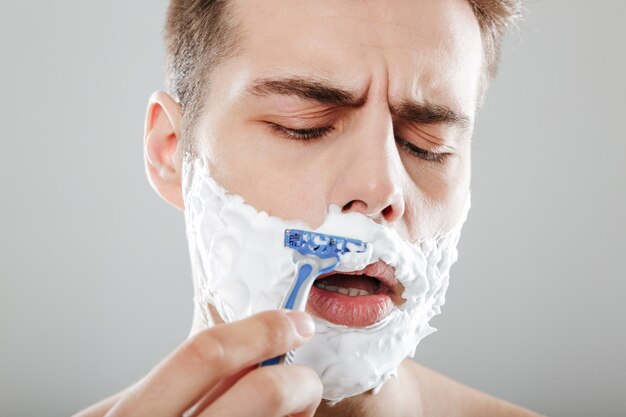 Close up portrait of a concentrated man with shaving foam