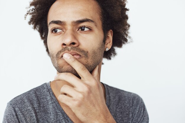 Close up portrait of concentrated serious african male thinking about past and future plans or dreaming where to go eat over white background.