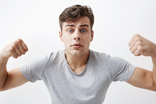 Free photo close up portrait of confident young caucasian male athlete with muscular body, demonstrating how strong he is, boasts of himself. good-looking sportsman shows his muscles and strength.