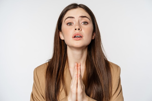 Close up portrait of corporate woman begging, pleading and saying please with desperate face expression, white background.