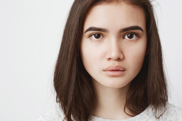 Close up portrait of cute teenage woman with serious and concentrated expression,