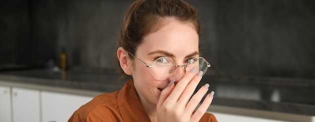 Free photo close up portrait of cute young woman in glasses covers her smile laughing and smiling giggle with