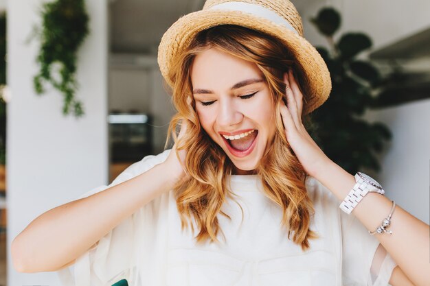 Close-up portrait of ecstatic curly girl wears trendy bracelet and wristwatch laughing with eyes closed