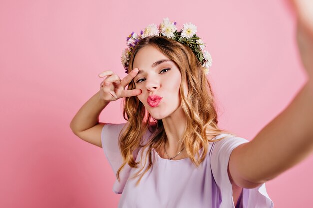 魅惑的な白人女性のクローズアップの肖像画は、流行の花の花輪を身に着けています