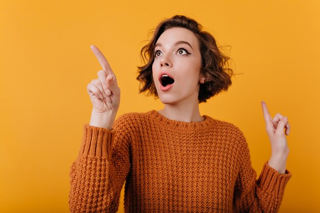 Close-up portrait of enthusiastic girl with suprised face expression looking around