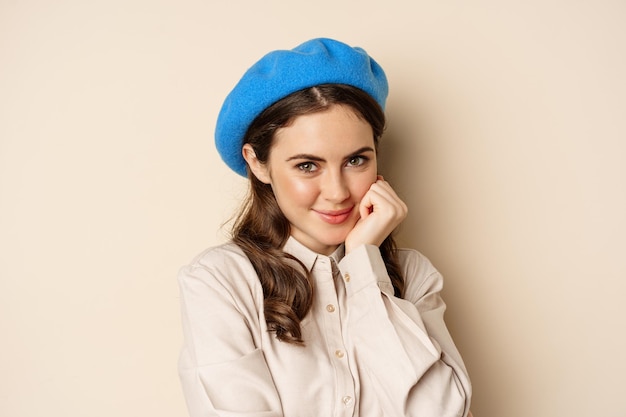 Close up portrait of feminine young woman in trendy french hat posing cute and romantic making silly...