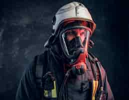 Free photo close-up portrait of a firefighter in safety helmet and oxygen mask. studio photo against a dark textured wall