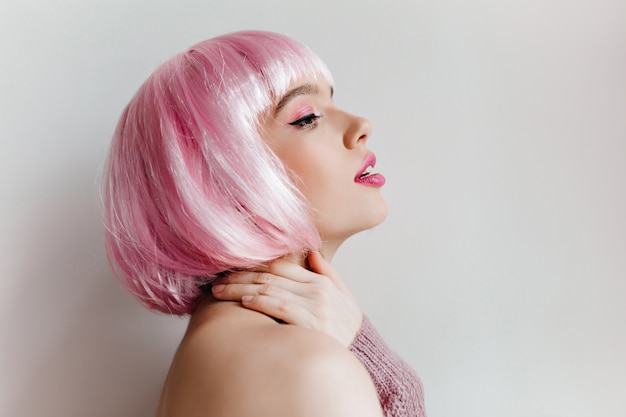 Free photo close-up portrait of  girl in colorful peruke dreamy looking away. winsome pale lady isolated on light wall.