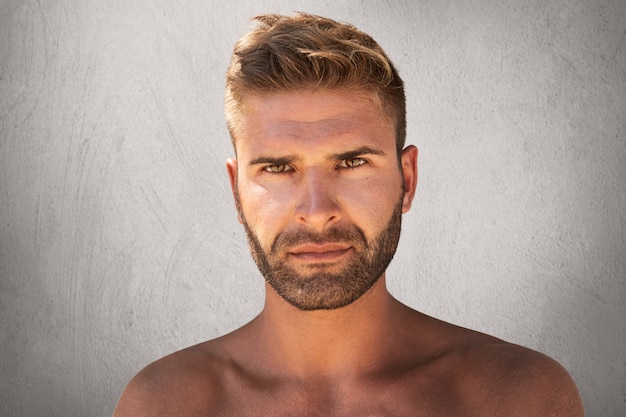 Free photo close up portrait of good-looking male with dark eyes, bristle and trendy hairdo being naked