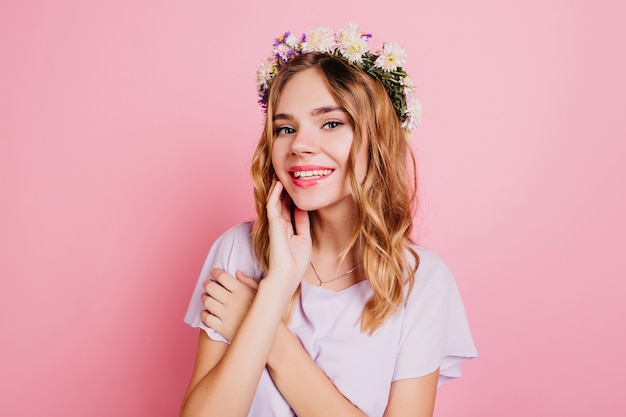 Close-up portrait of good-looking white woman in circlet of flowers smiling to camera