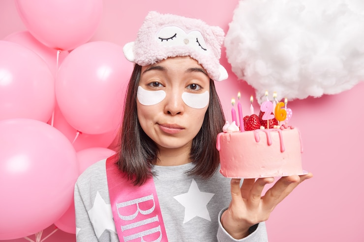 Free Photo close up portrait of good looking young asian female model applies patches under eyes wears sleepmask and pajama celebrates birthday