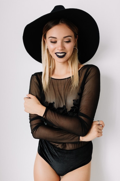 Free photo close-up portrait of gorgeous blonde young woman wearing black hat and bodysuit