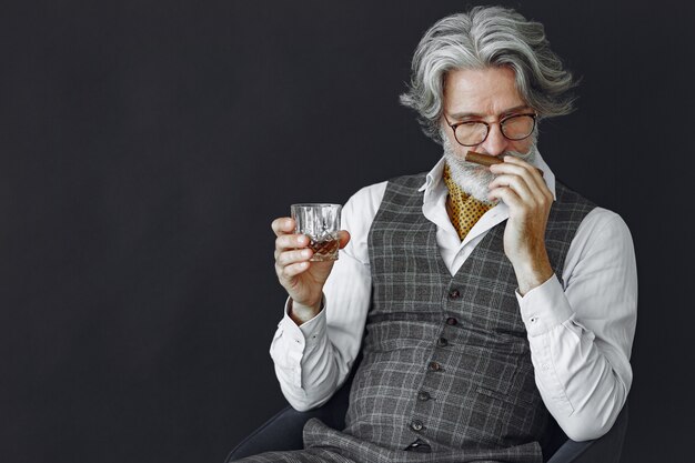 Close up portrait of grinning old-fashioned man.  Grandfather with a cigar and whiskey.